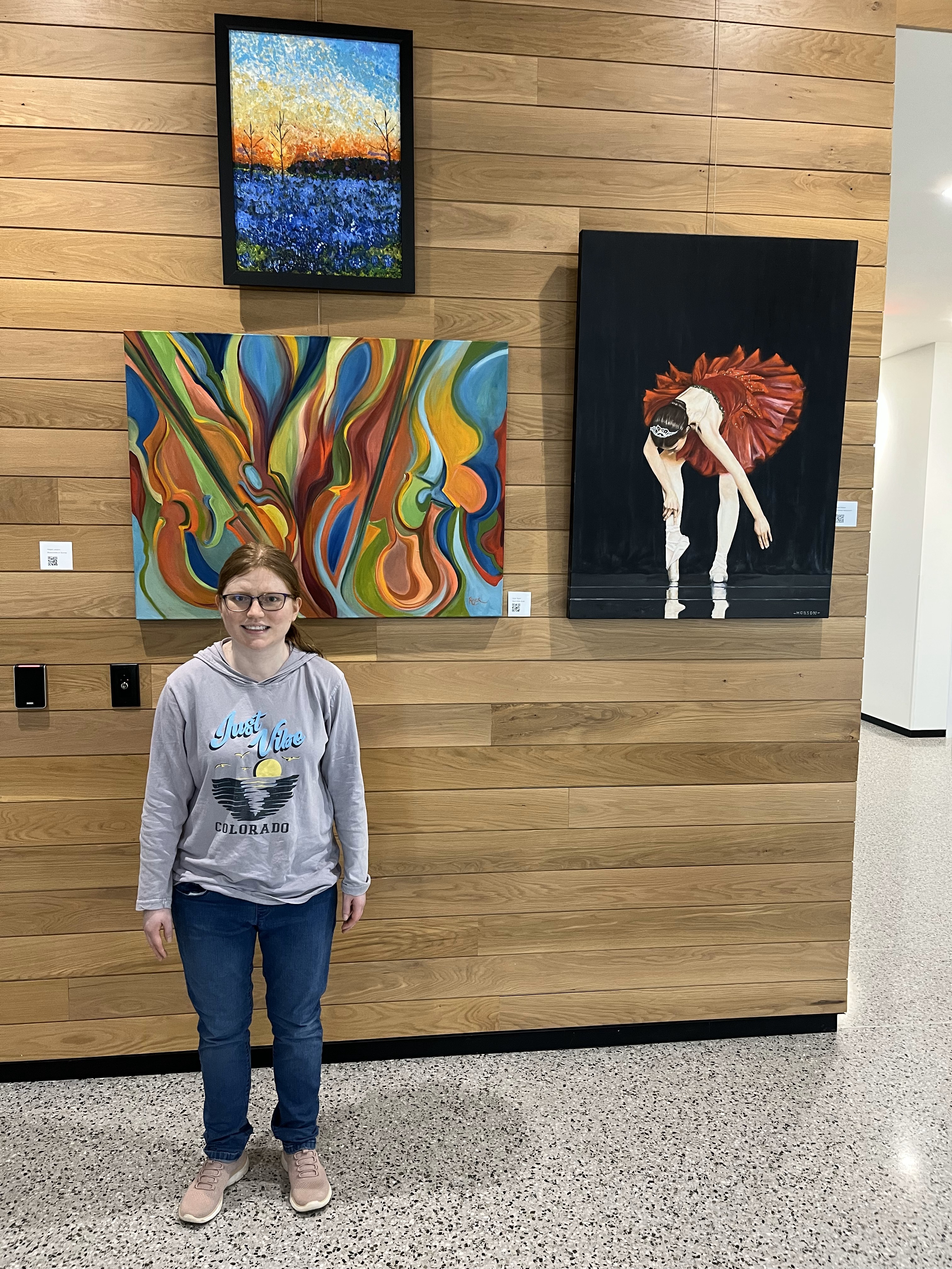 A redheaded woman standing next to her painting at the new city hall